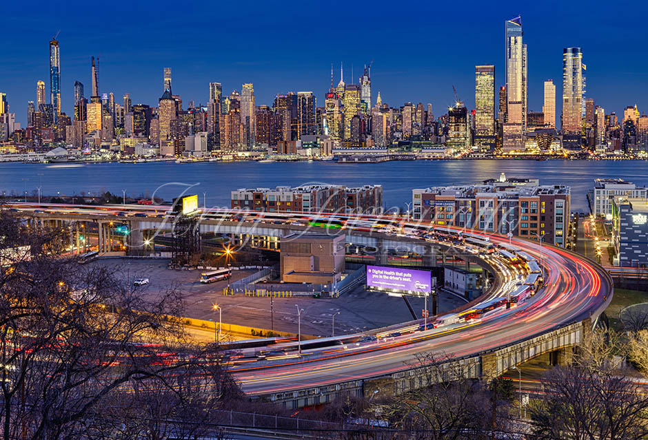 Traffic and light trails on "The Helix", a highway loop at the entrance in Lincoln Tunnel. The New York skyline shines in the background.