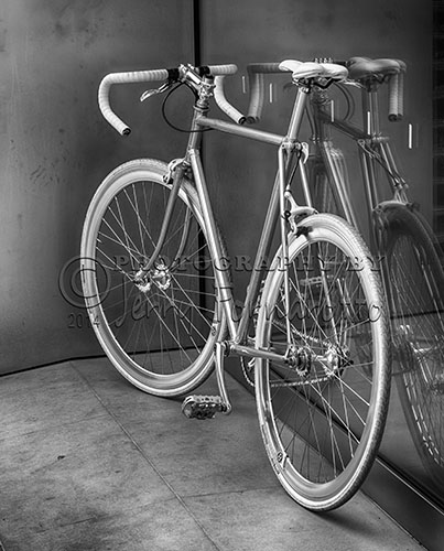 A black and white photo of a sleek looking bicycle in front of the Apple Store, Charleston, SC.