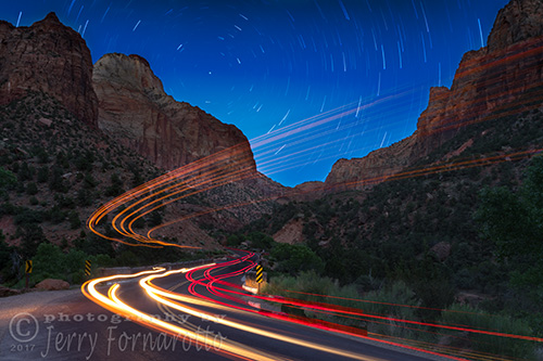 A long exposure photo of car light trails traveling through Zion National Park, Utah.