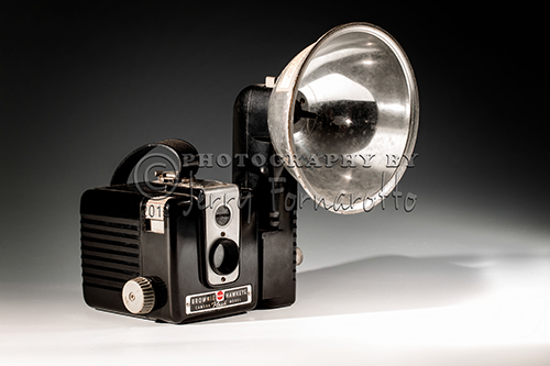 A still life photo of an old Brownie Hawkeye camera with flash. Brownie is the name of a long-running popular series of simple and inexpensive cameras made by Eastman Kodak. The Brownie popularized low-cost photography and introduced the concept of the snapshot.