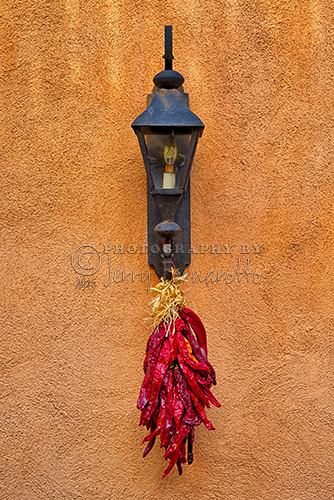 A bunch of dried chili peppers hanging from a lamp.