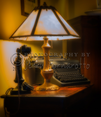 A photo of a ninteen-twenties phone, old reading lamp and Royal typewriter.