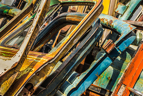 A stack of old rusty car doors found in a car junk yard.