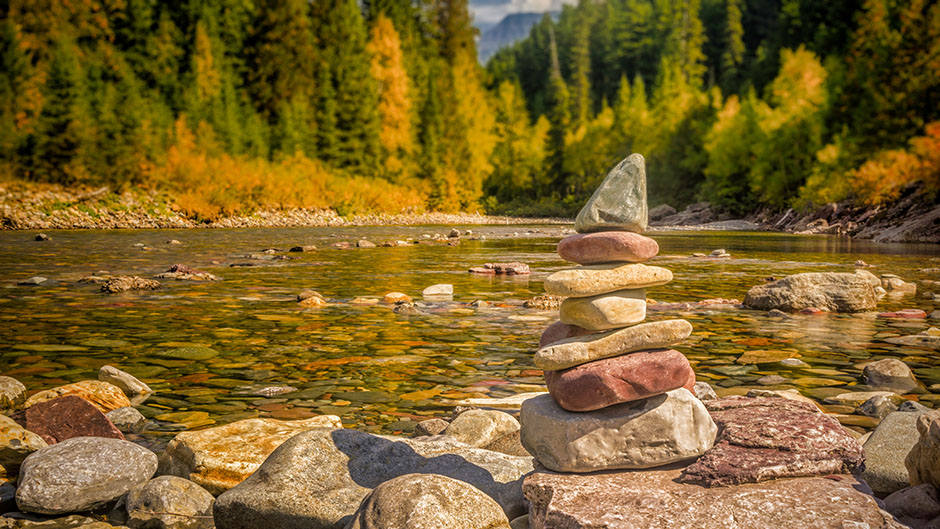 A carin is a stacked pile of stones to mark a trail. This one marks a trail that crosses a shallow river in Glacier National Park.
